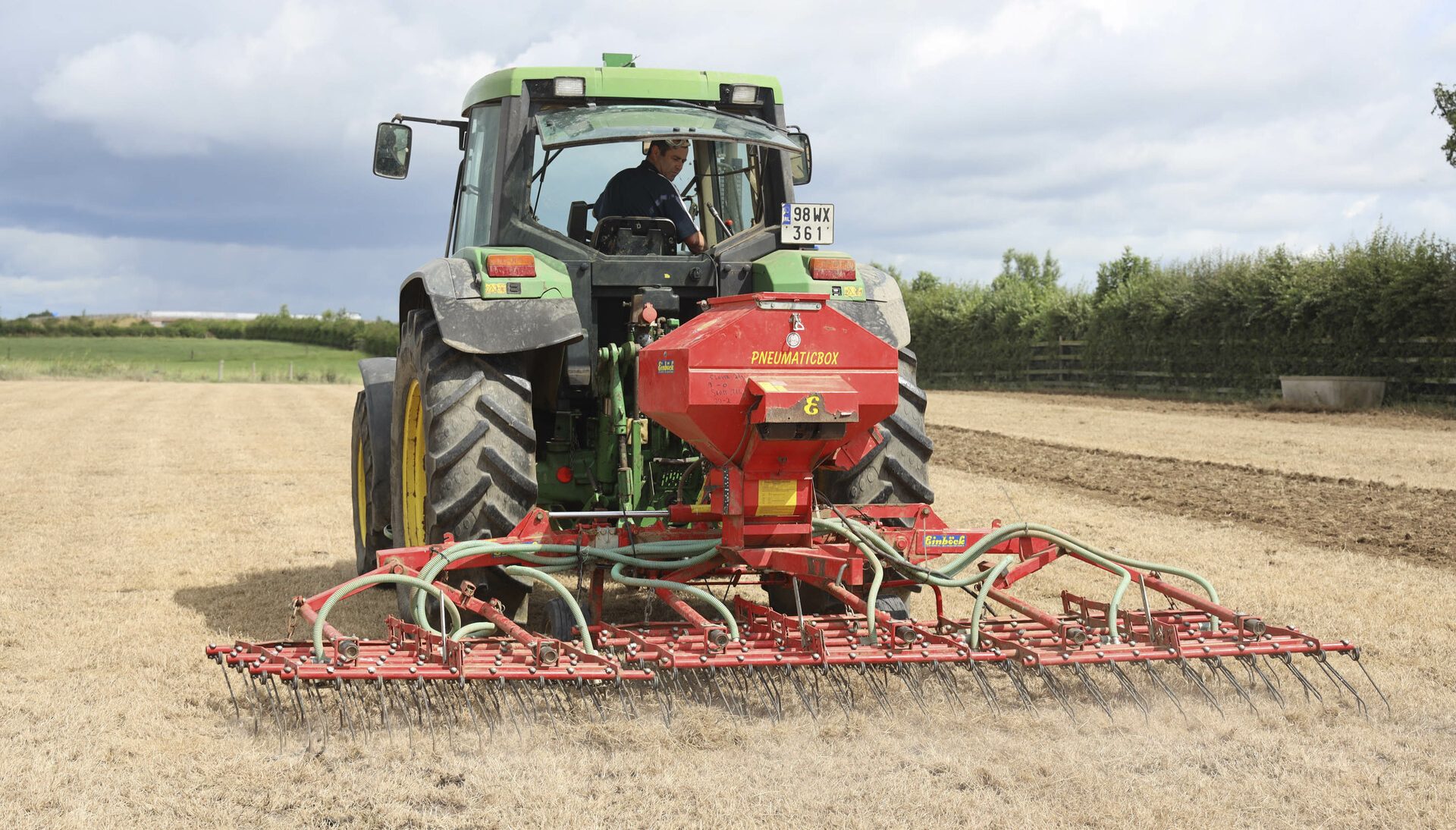 Tractor direct drilling seed in a field.