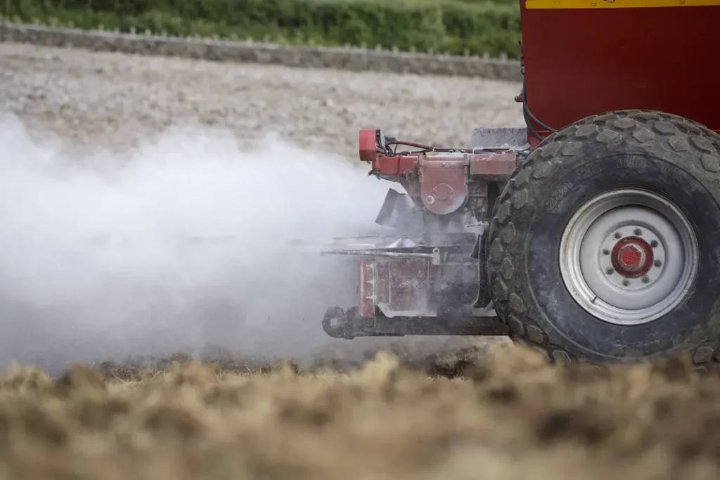 A tractor applying lime to soil as part of the grassland reseeding process